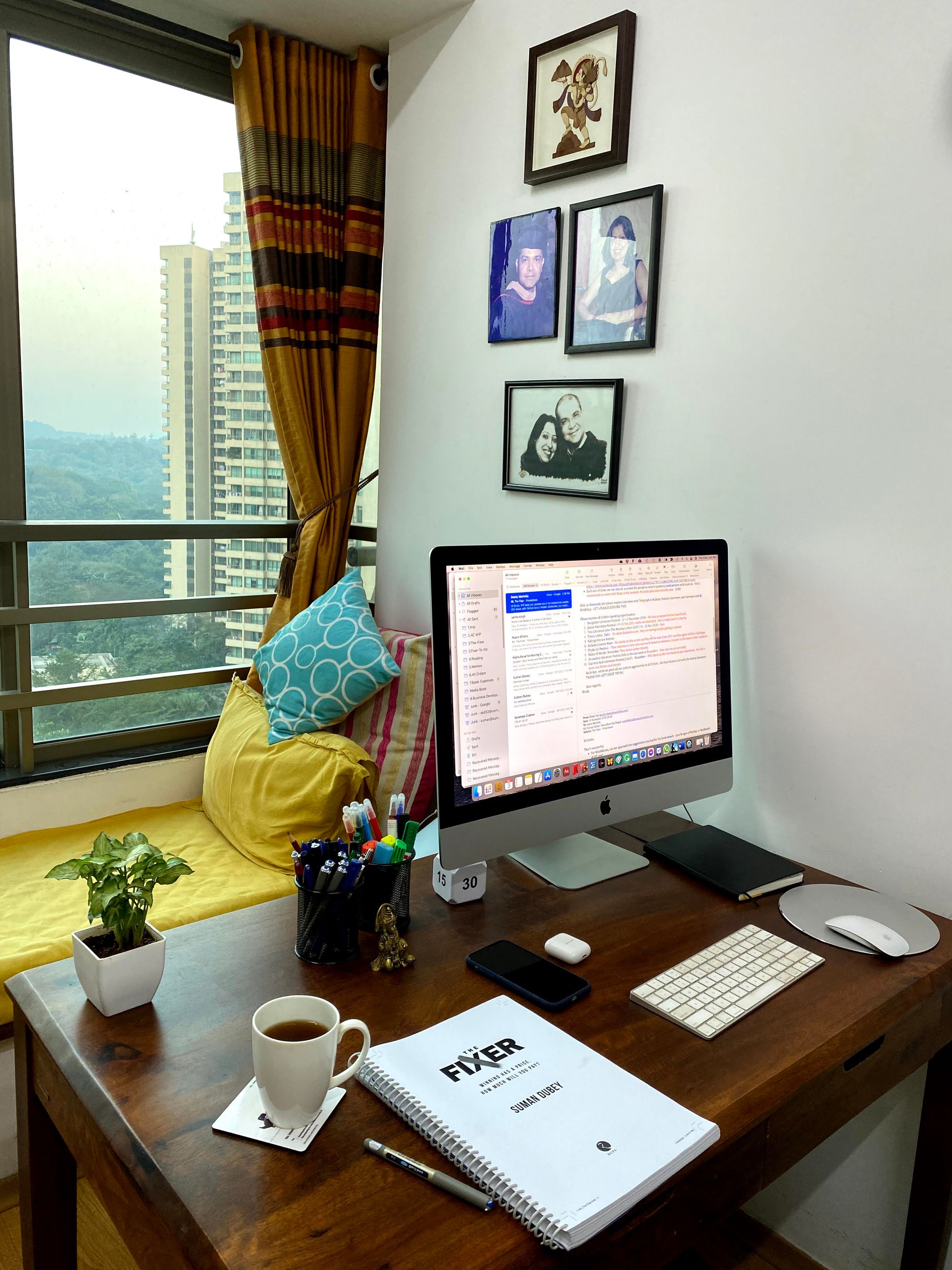 Image showing Suman Dubey’s workplace: a wooden desk with an iMac, a mug and the manuscript for “The Fixer”.  